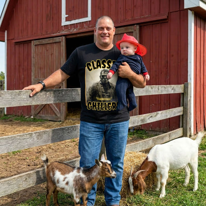 "Frankenstein" black t-shirt with gothic horror monster graphic and classic chillers logo; front view; on model with baby and goats in front of red barn.
