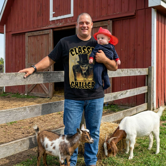 "Sinister Mr Hyde" black t-shirt with gothic man of murder graphic and classic chillers logo; front view; on model with baby and goats in front of red barn.
